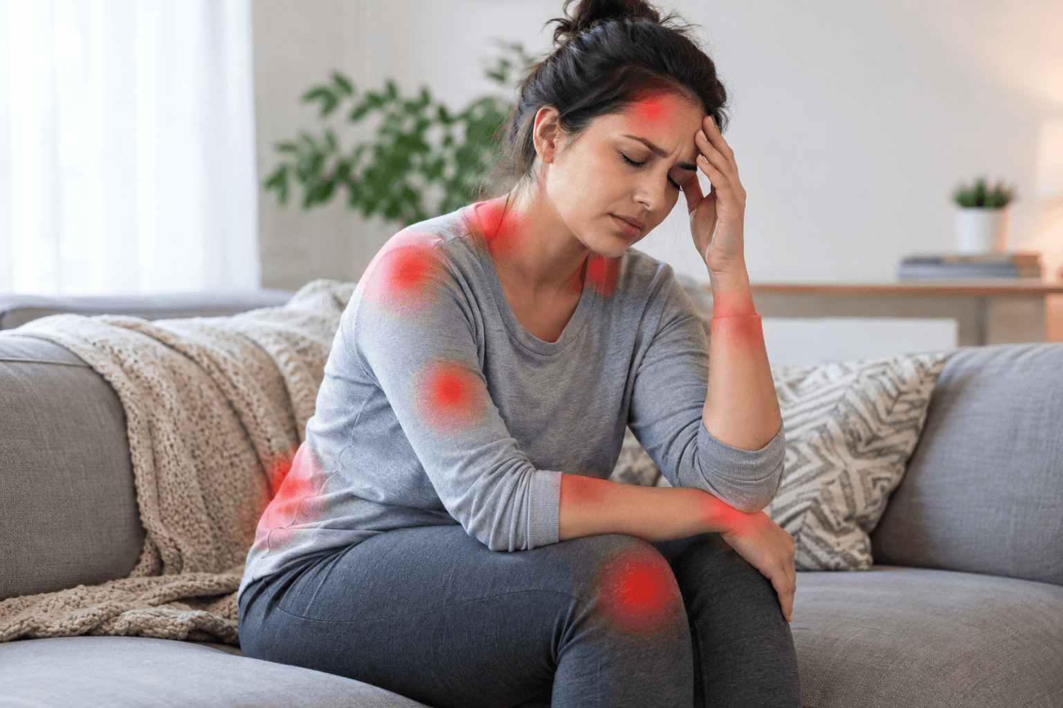 Woman sitting on a couch with widespread pain highlighted on her body